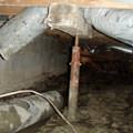 Rusty steel crawl space jack post supports in a structure in Fredericksburg.
